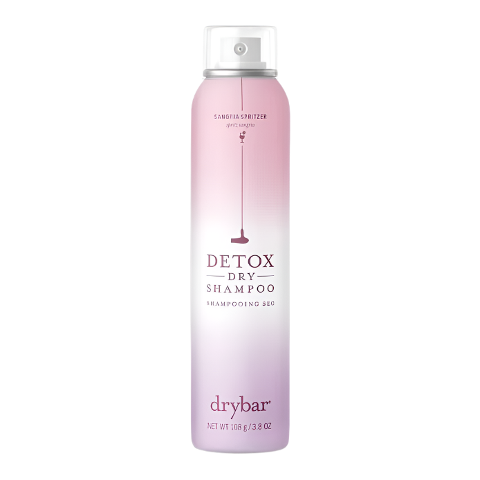 A full-size bottle of Drybar Detox Dry Shampoo in Sangria Spritzer scent, presented in a white and pink ombre design with a martini glass illustration, indicates the product weight is 108g/3.8oz.