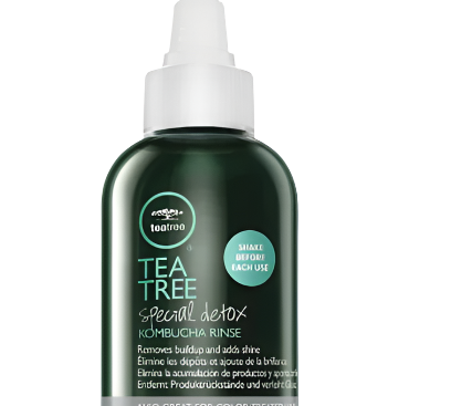 A 75 ml bottle of Tea Tree Special Detox Kombucha Rinse, designed with a pointed applicator, comes in a green bottle with white text detailing its benefits of removing buildup and enhancing shine. It's suitable for all hair types, including color-treated hair.