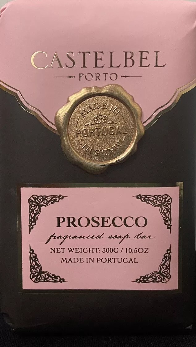 A package of Castelbel Editions Prosecco fragranced soap bars features two 7oz bars with a design that includes a pink and black color scheme, decorative details, and a gold wax seal. The label indicates it is made in Portugal.